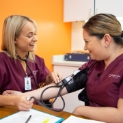 Smiling medical assistant students taking blood pressure