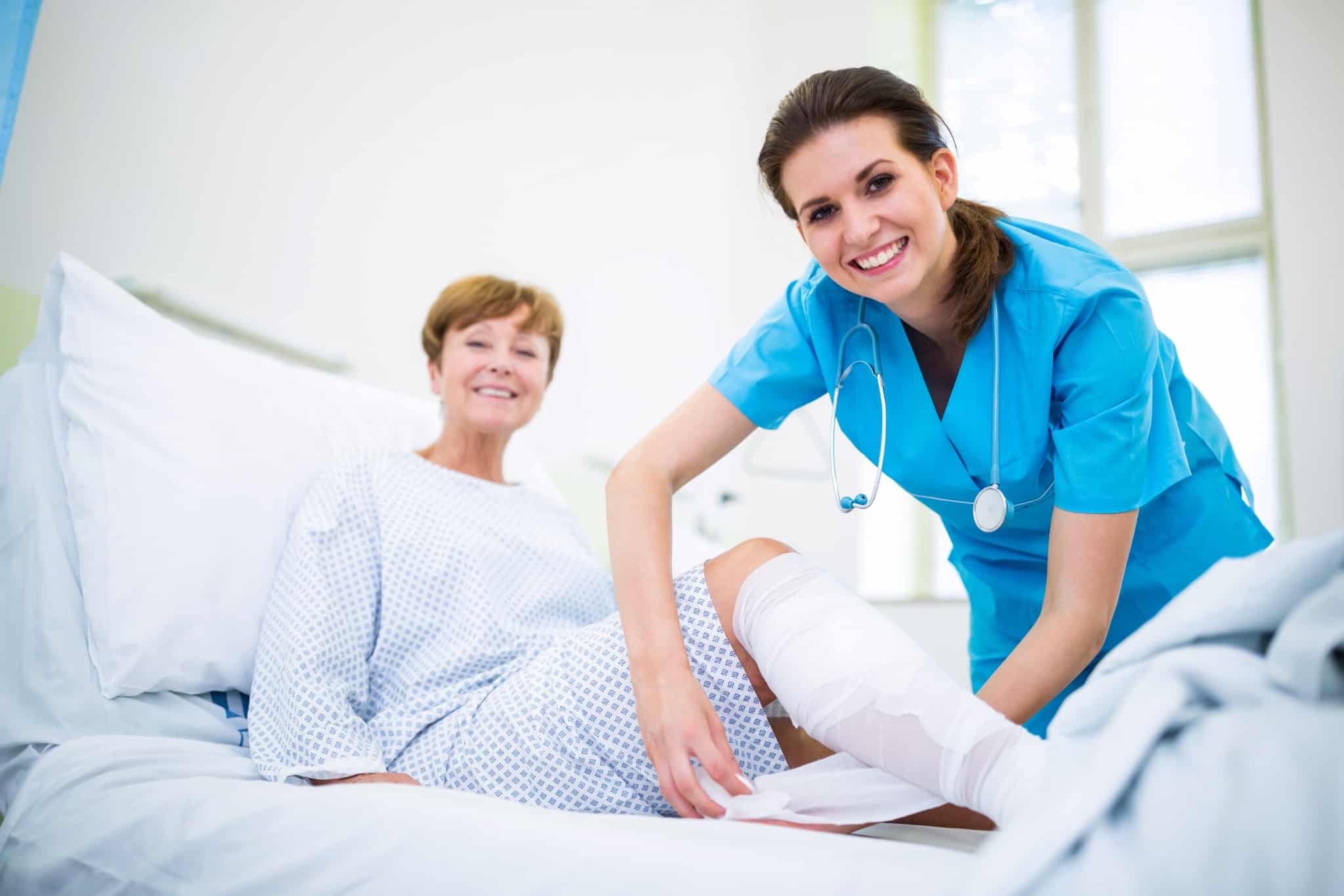 Nurse bandaging the leg of patient