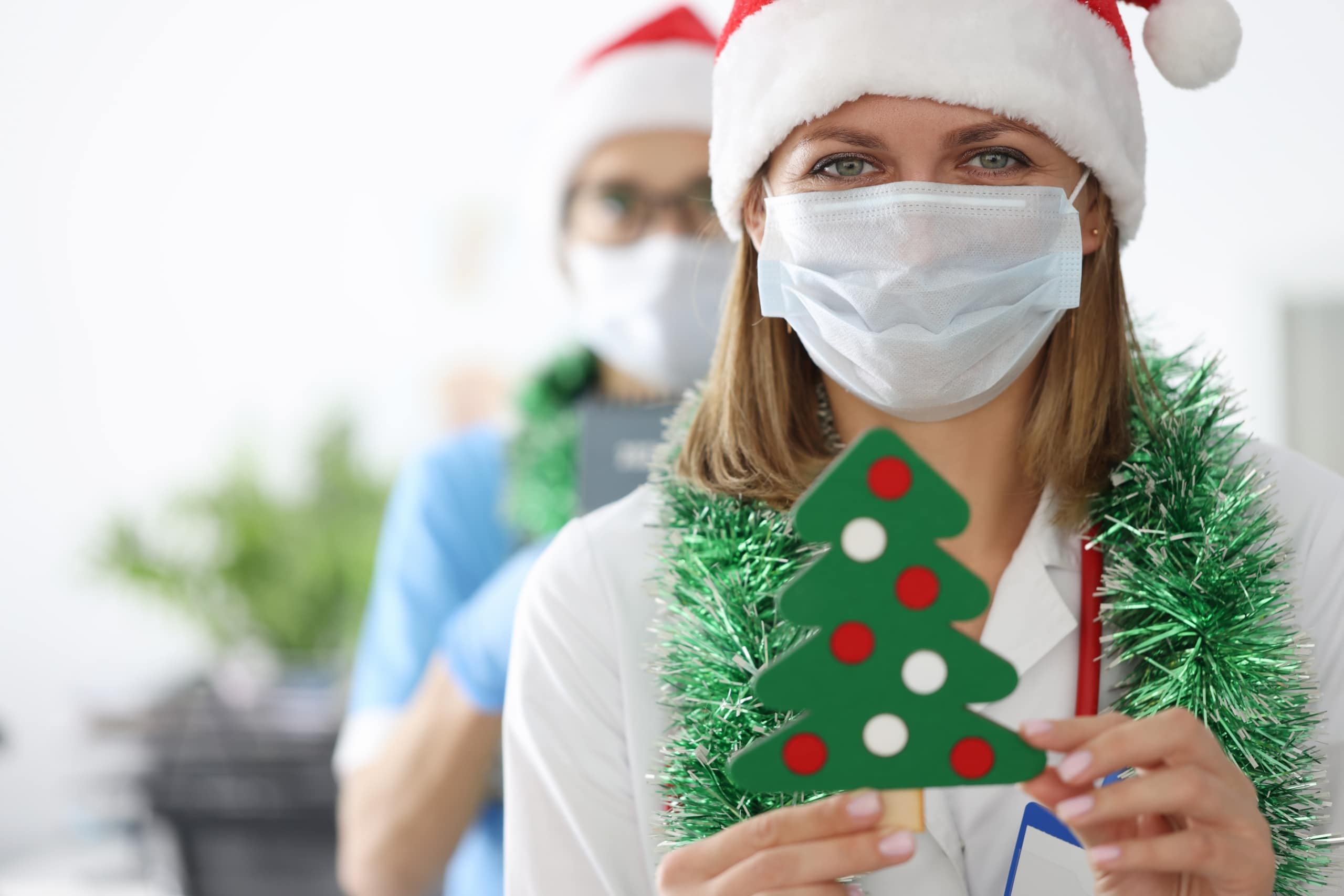 Nurse in a Santa hat holding a small tree