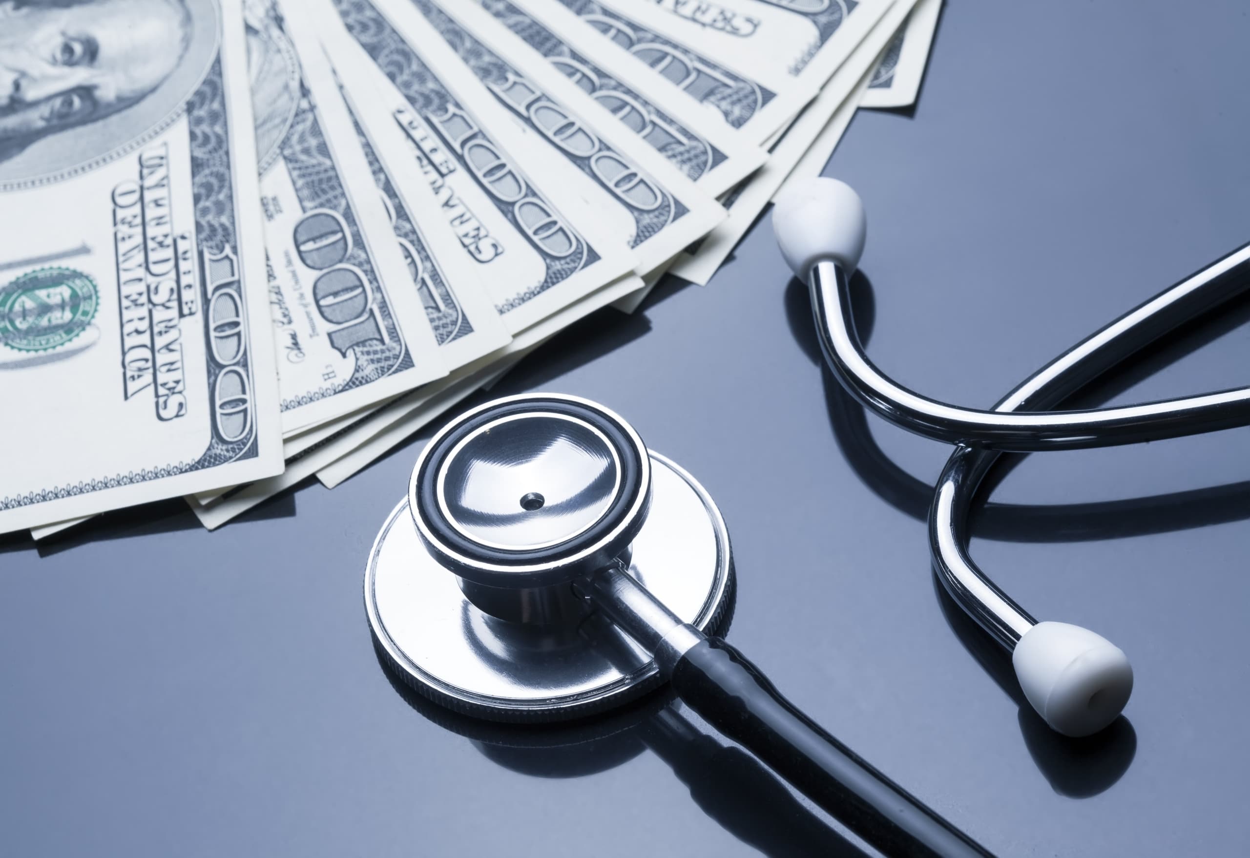 Close up of stethoscope and stack of bills