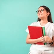 Smiling medical student with textbooks against a blue background