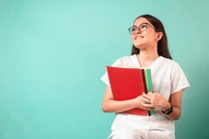 Smiling medical student with textbooks against a blue background