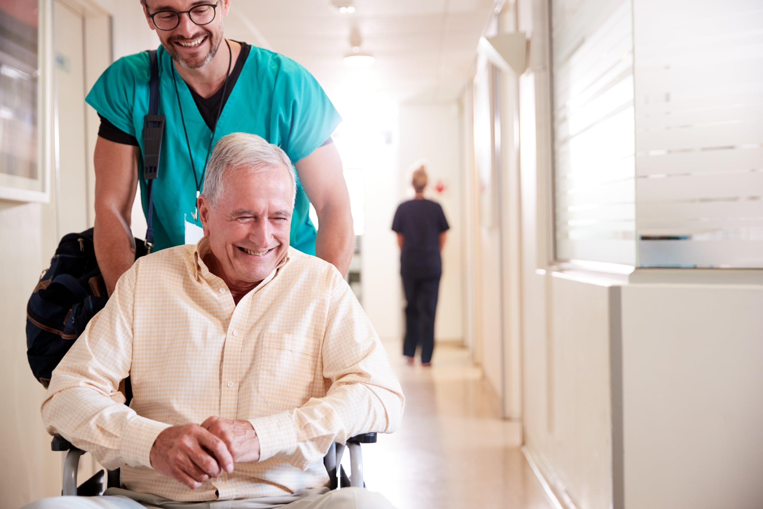 Medical professional pushing an elderly man's wheelchair