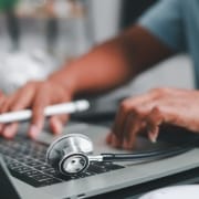 Close up of a male nurse with a stethoscope using a laptop