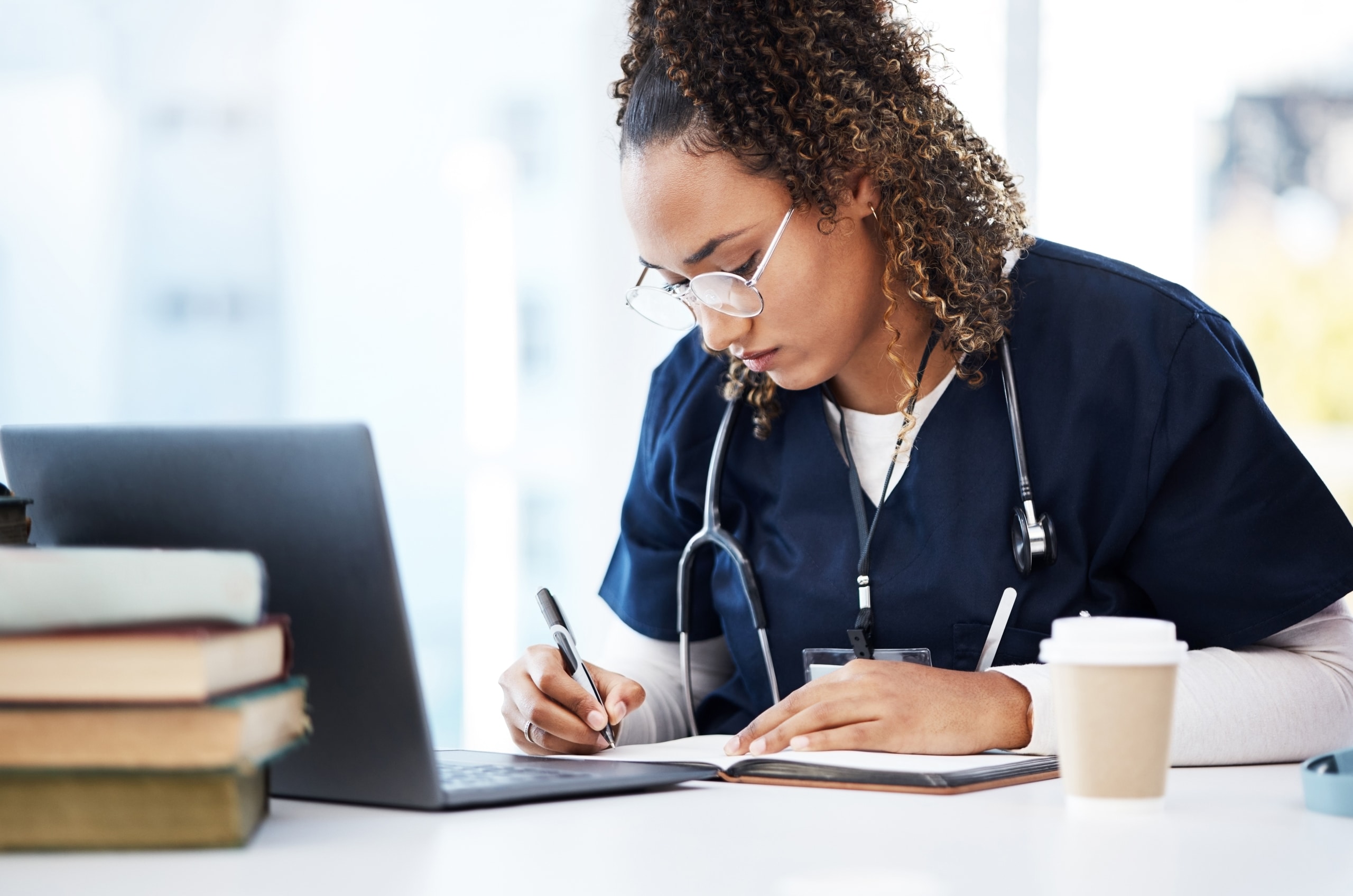 African-American nurse wearing glasses and studying with a laptop