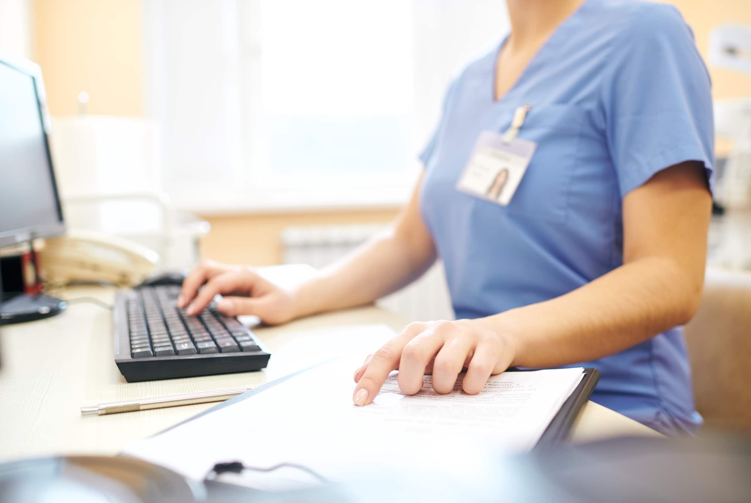 Close up of a nurse typing on a computer