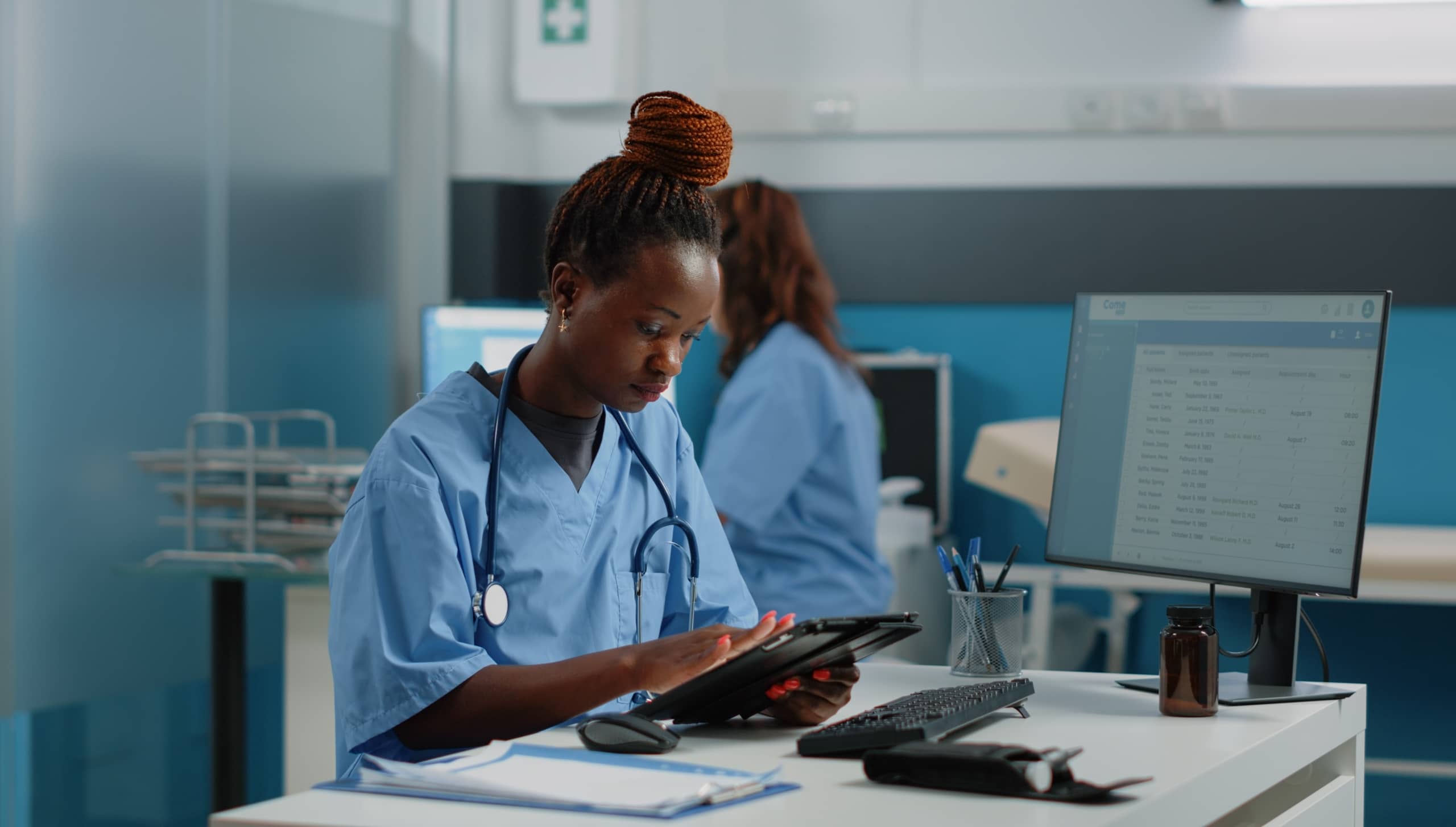 African-American nurse using a tablet at a desk