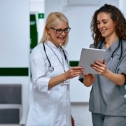 Female nurse and doctor discussing paperwork in a hallway