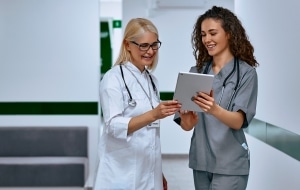 Female nurse and doctor discussing paperwork in a hallway