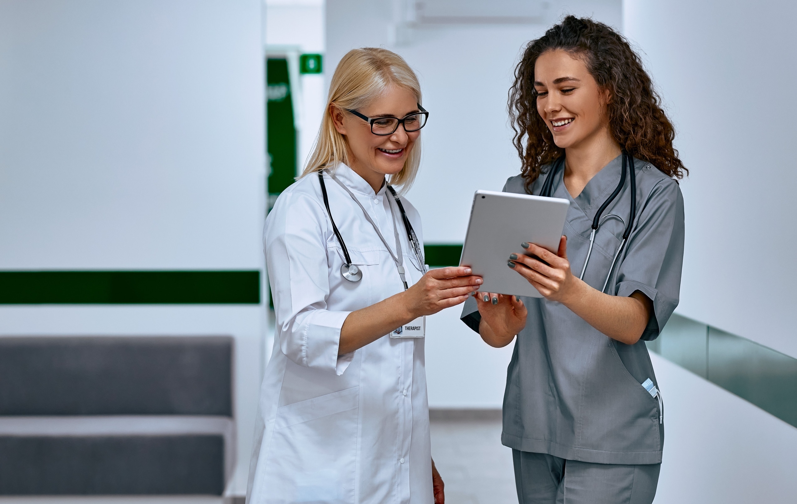 Female nurse and doctor discussing paperwork in a hallway