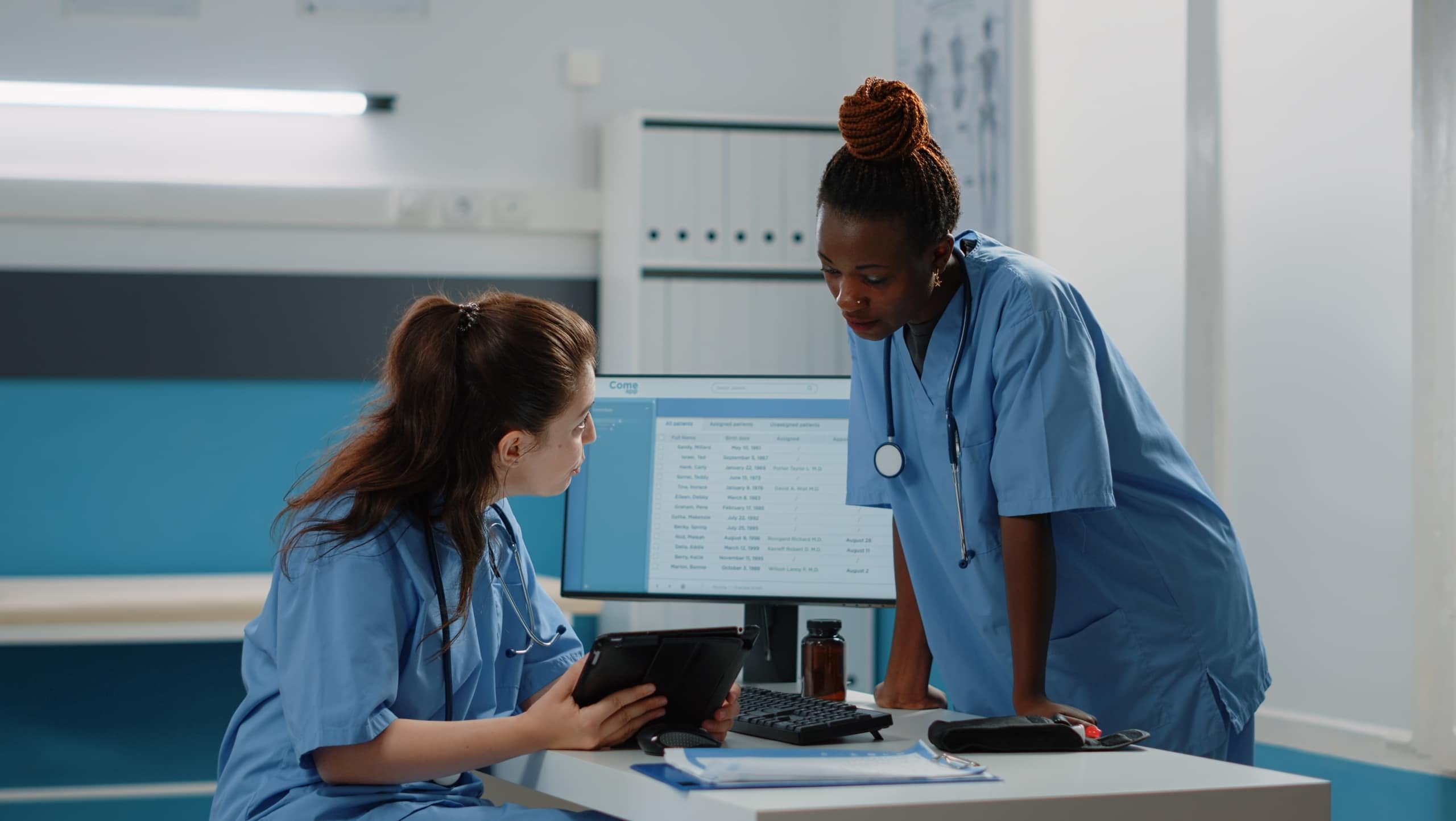 Two female nurses speaking at a desk