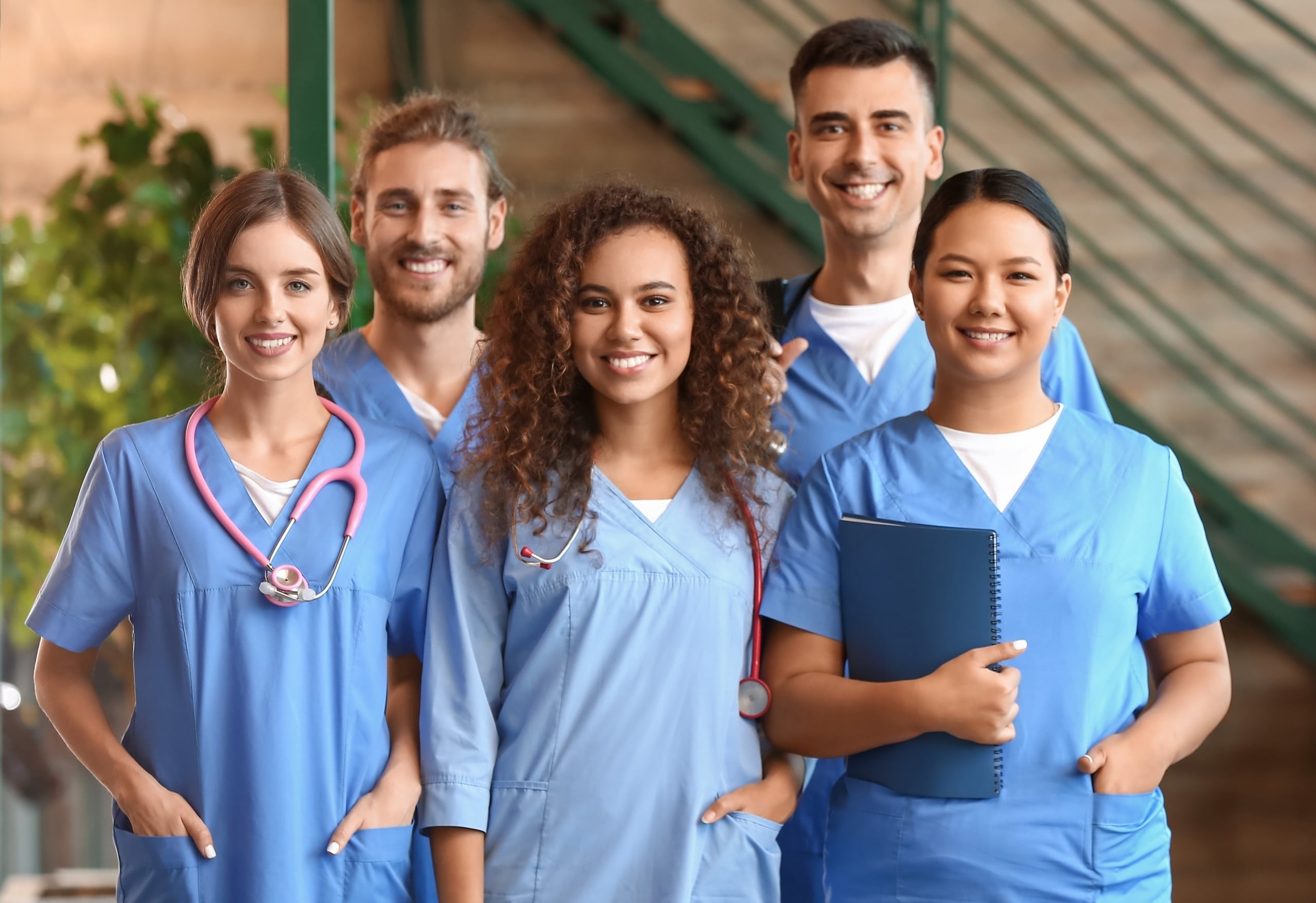 Group of smiling medical professionals in front of an outdoor stairwell