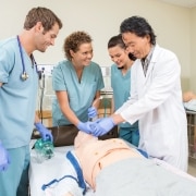 Asian instructor with students using a medical mannequin