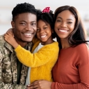 African-American military veteran smiling with wife and daughter