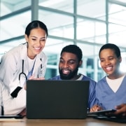 Medical professionals standing around a laptop
