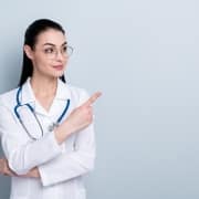 Professional nurse pointing to the side against a solid backdrop