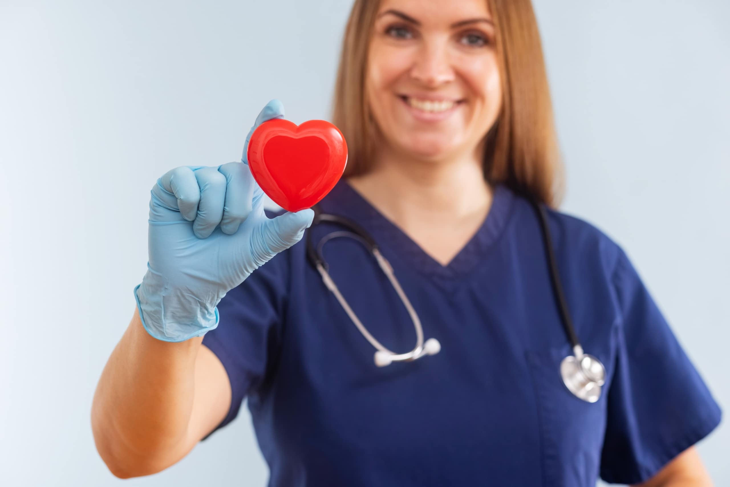 Nurse in scrubs holding a miniature heart