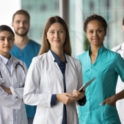 Smiling group of medical professionals wearing scrubs and white coats