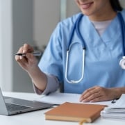 Close up of a female nurse pointing at her laptop with a pen