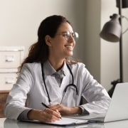 Young medical professional smiling and using a laptop