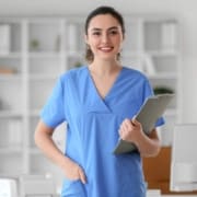 Young female nurse in blue scrubs with a clipboard