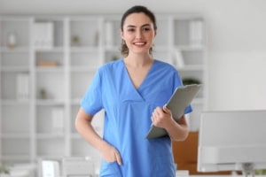 Young female nurse in blue scrubs with a clipboard